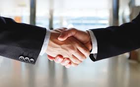 Two business professionals shaking hands in a modern office setting